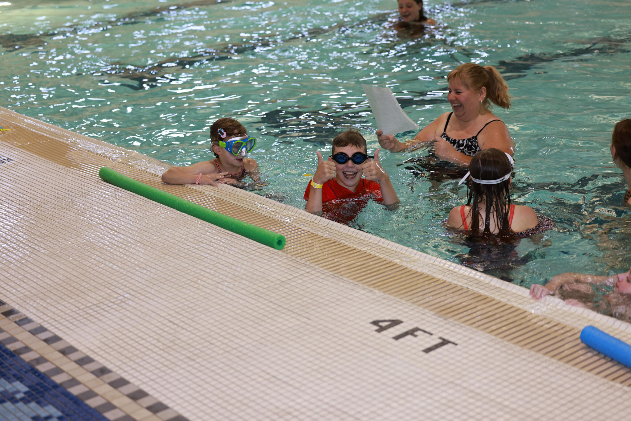 An instructor teaching children to swim.